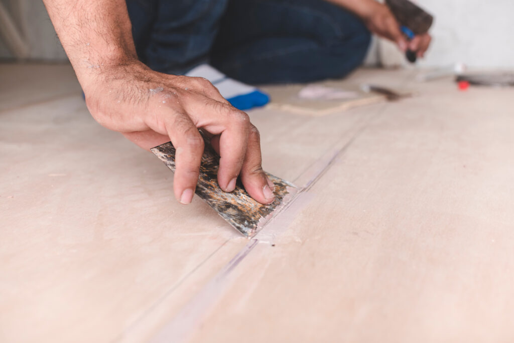 A carpenter filling gaps in wood floors. At the attic, home renovation, restoration or construction.