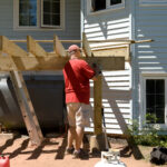 A man is building a back deck on his own in summer