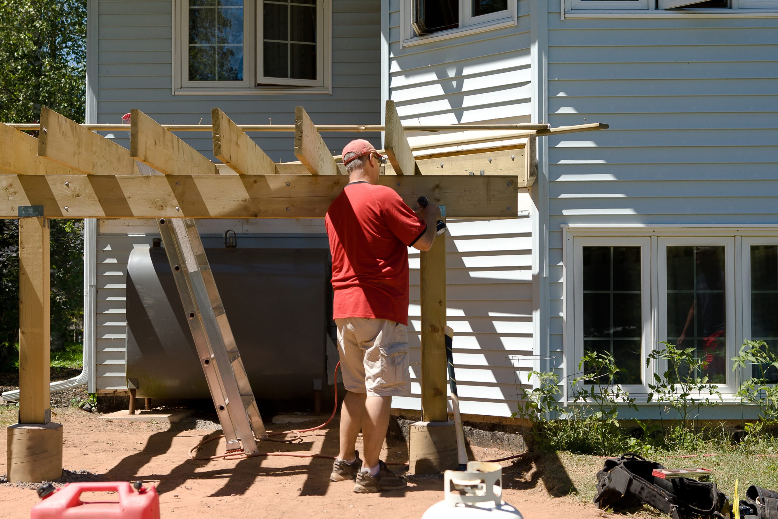 A man is building a back deck on his own in summer