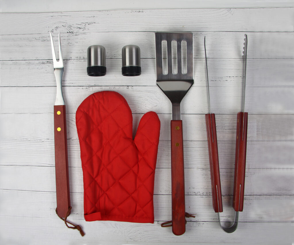 BBQ instruments kit close up isolated on white wooden background flat lay