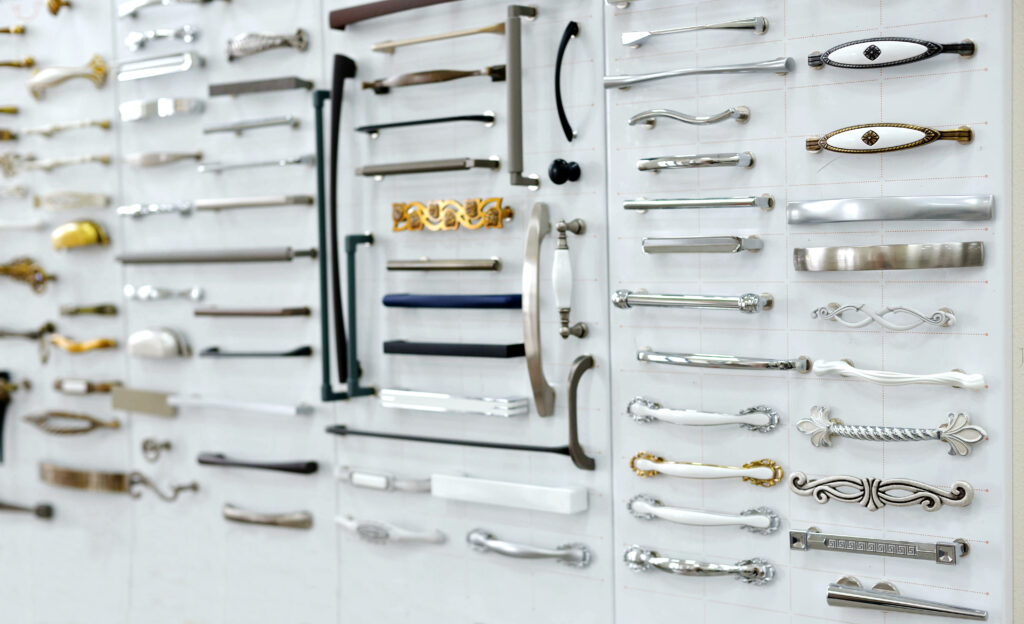 Big selection of handles cabinets parts on a white background shop window. samples of Metal and Stainless Steel handle styles on wooden kitchen cabinet with different Stainless Steel handles