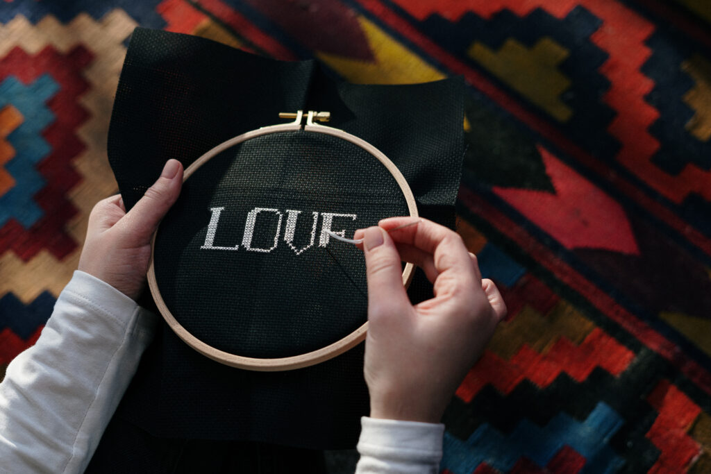 Close up of a person doing embroidery work on black fabric