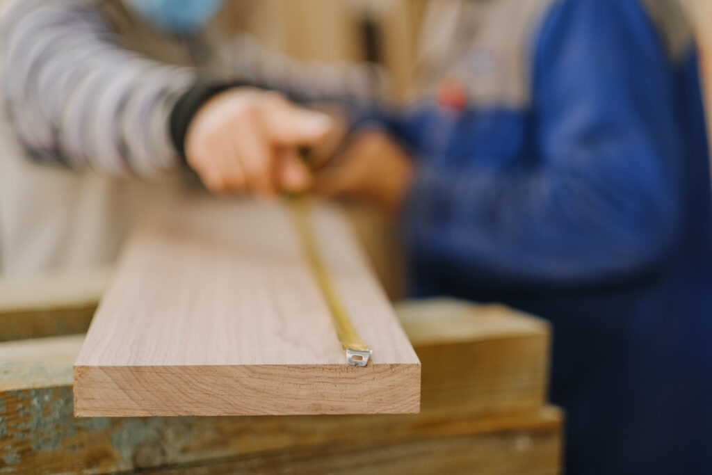 Closeup shot of a carpenter measuring on a piece of plywood