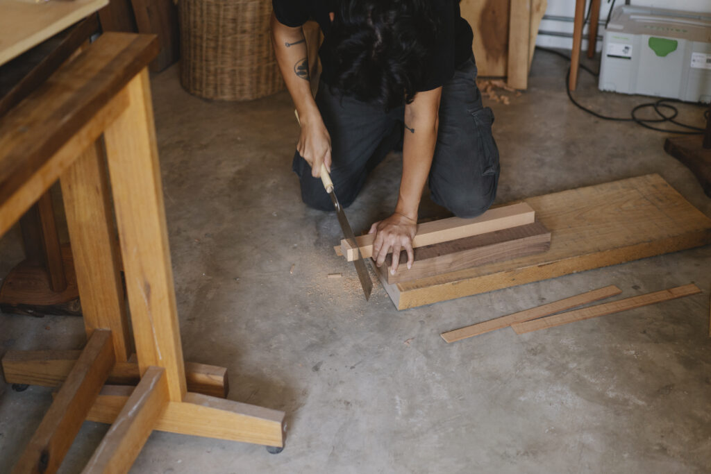 Crop artisan cutting piece of hardwood