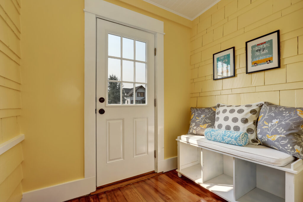 Entryway with yellow walls and storage bench in white