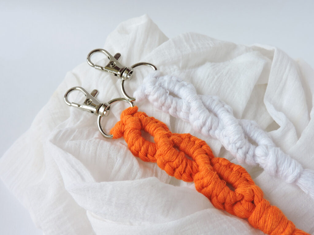 Macrame keychain made of cotton thread. Handcrafted work. Decoration Artworks. Handicrafts. Macrame art for gift. Keychain isolated on a white background. Handmade souvenir.