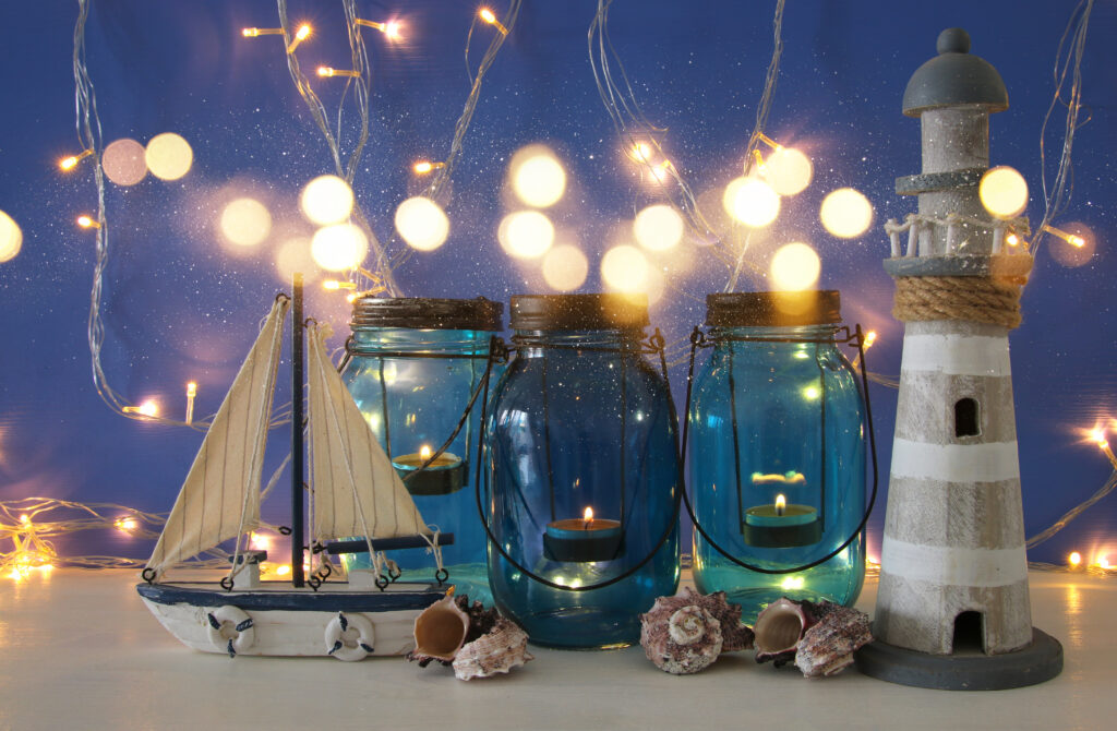 Magical mason jars whith candle light and wooden boat on the shelf. Nautical concept