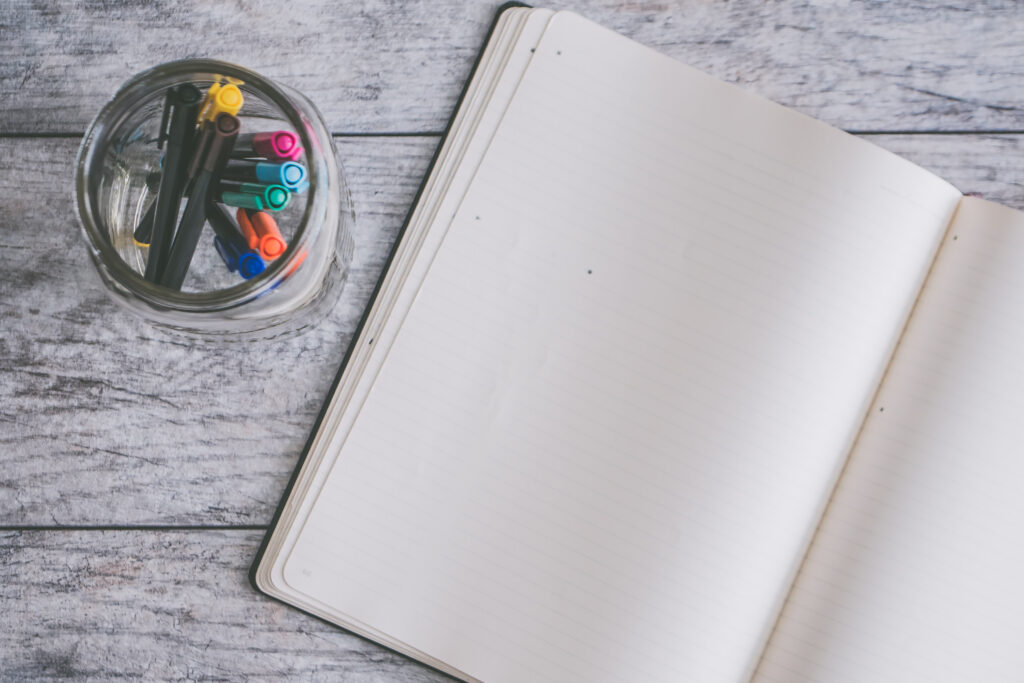 Photo of blank note book near clear jar