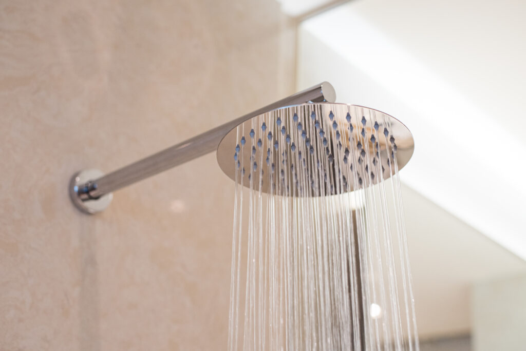 Shower turned on, overhead ceiling shower faucet head closeup.