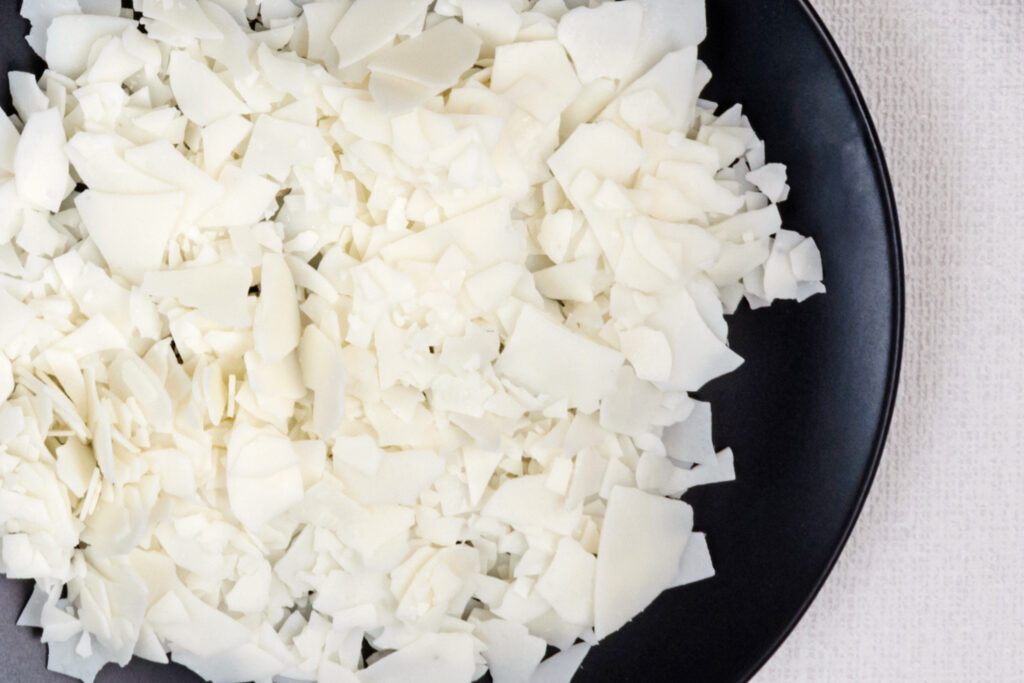 Soy wax - ingredient for handmade candles on black plate and white background