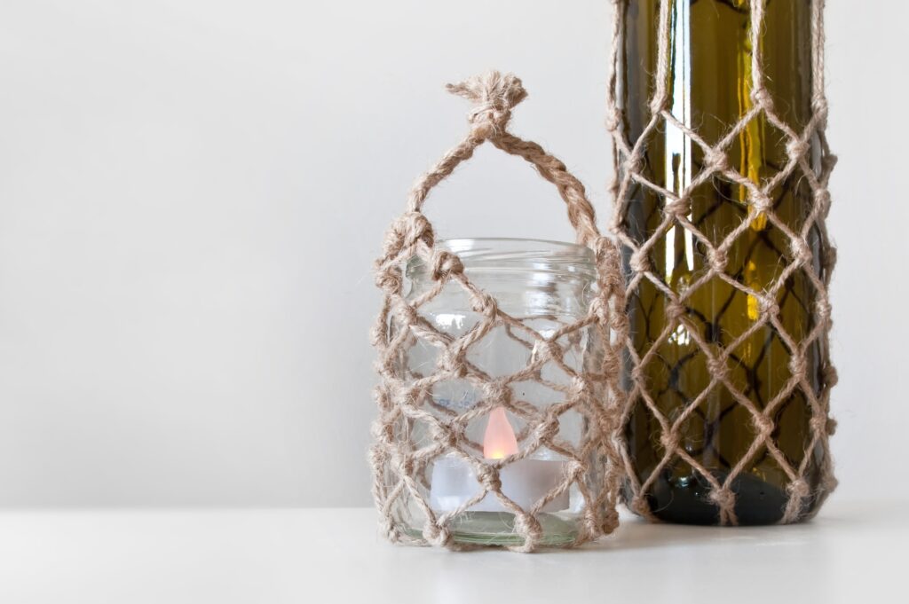 Summer homemade decoration, glass jar and bottle with macrame knotting cord of twine as decorative cover. Shallow depth of focus. Season concept, handmade art set.