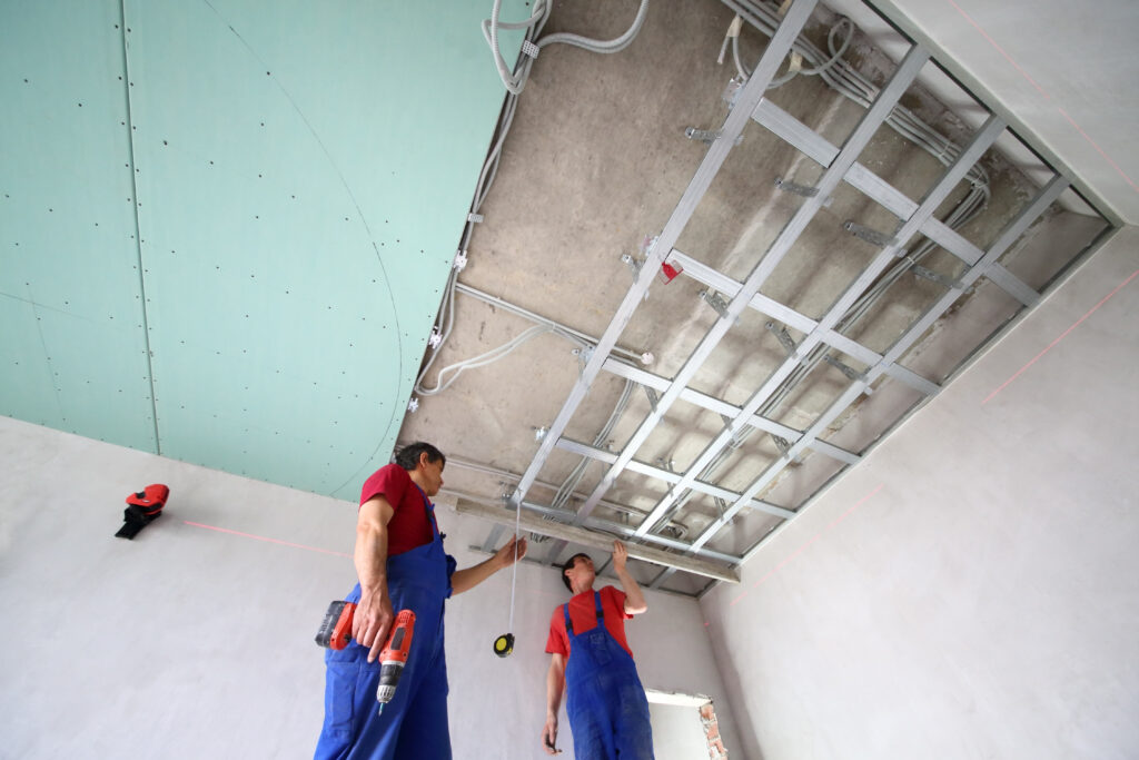 two workers set the ceiling profile in the new flat