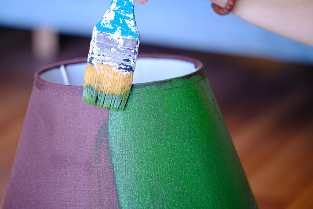 Woman painting lampshade green with brush. Do it yourself concept.