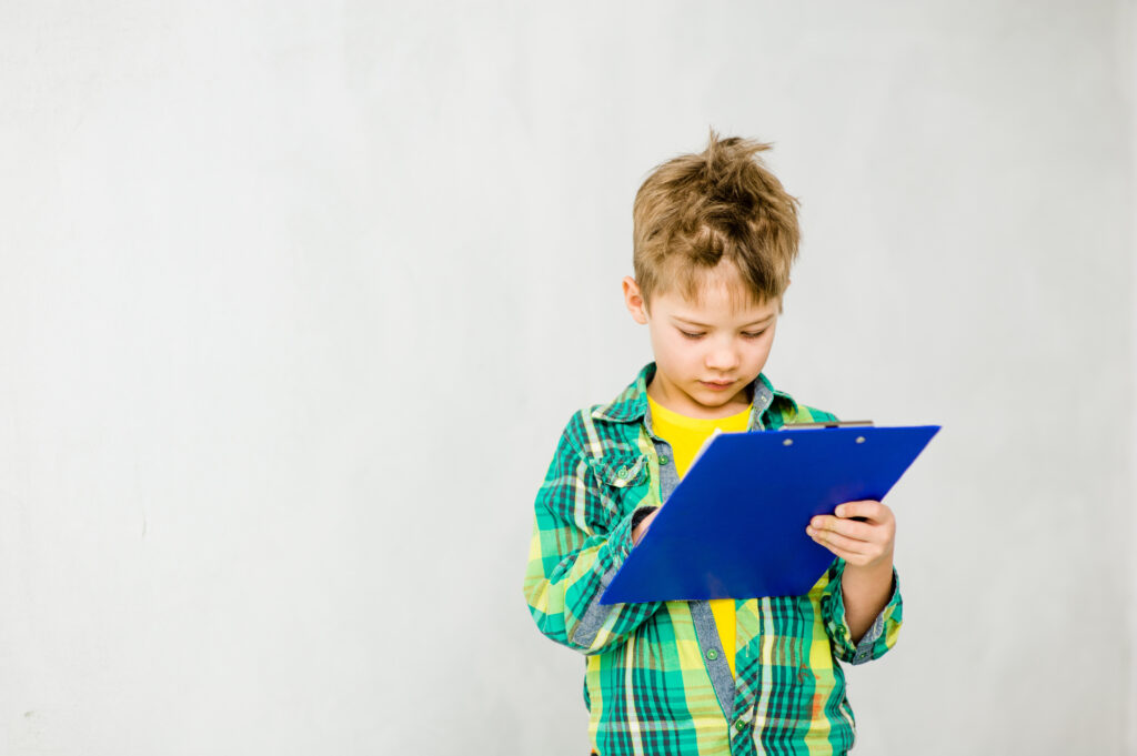 Young boy writing in a clipboard. Space for text