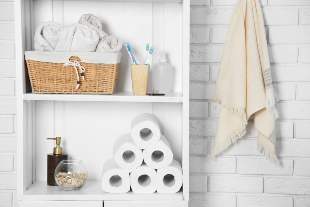 Bathroom set with towels, toothbrushes and basket on a shelf in light interior