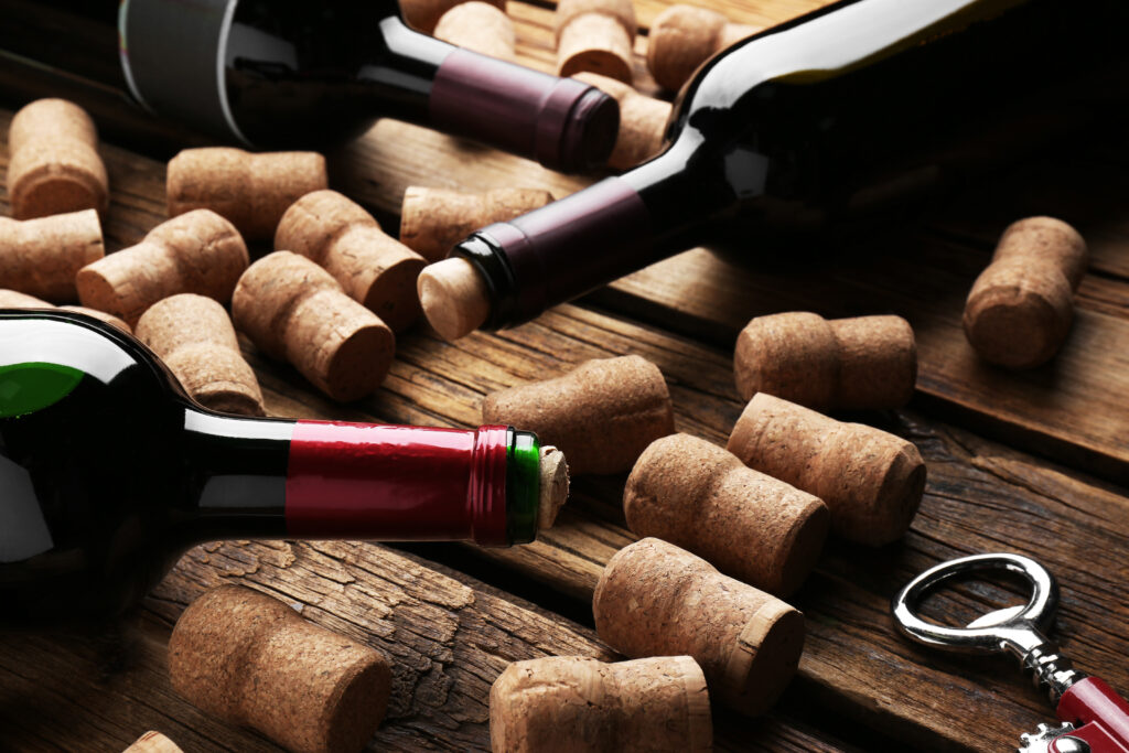 Bottles with wine, corkscrew and corks on wooden table