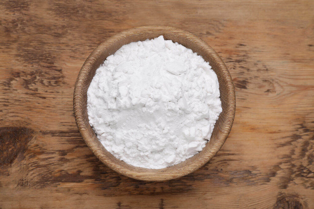 Bowl of natural starch on wooden table, top view