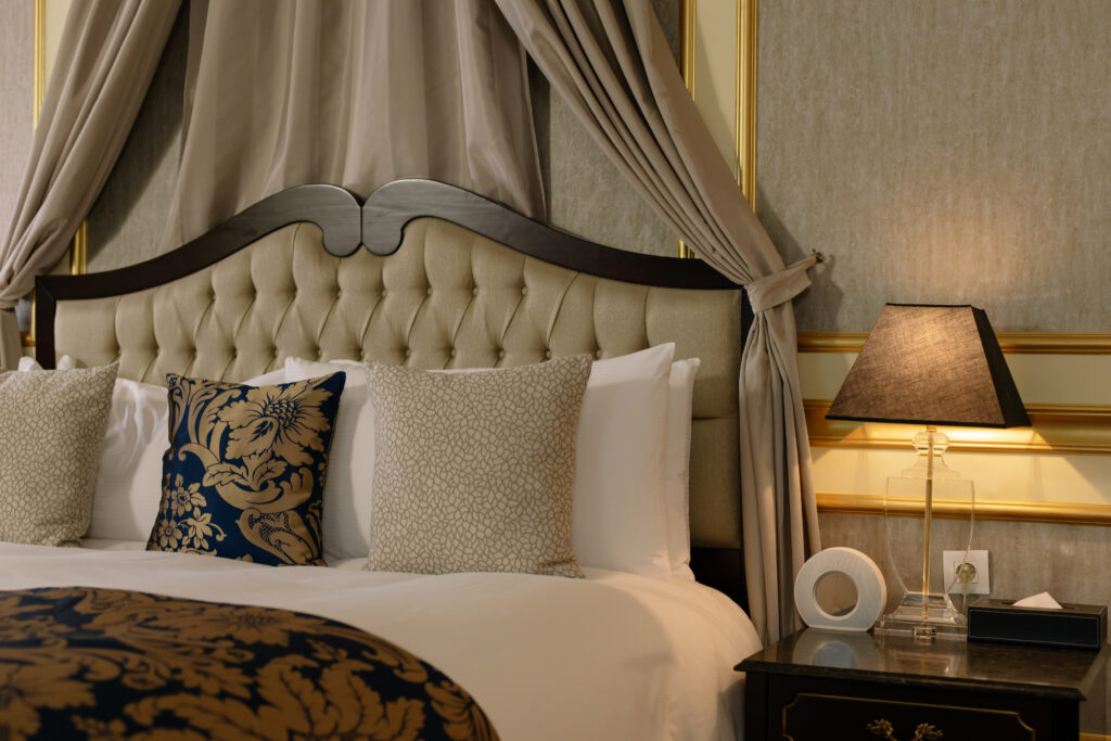 Classic wooden bed beside a black side table with lighted night lamp