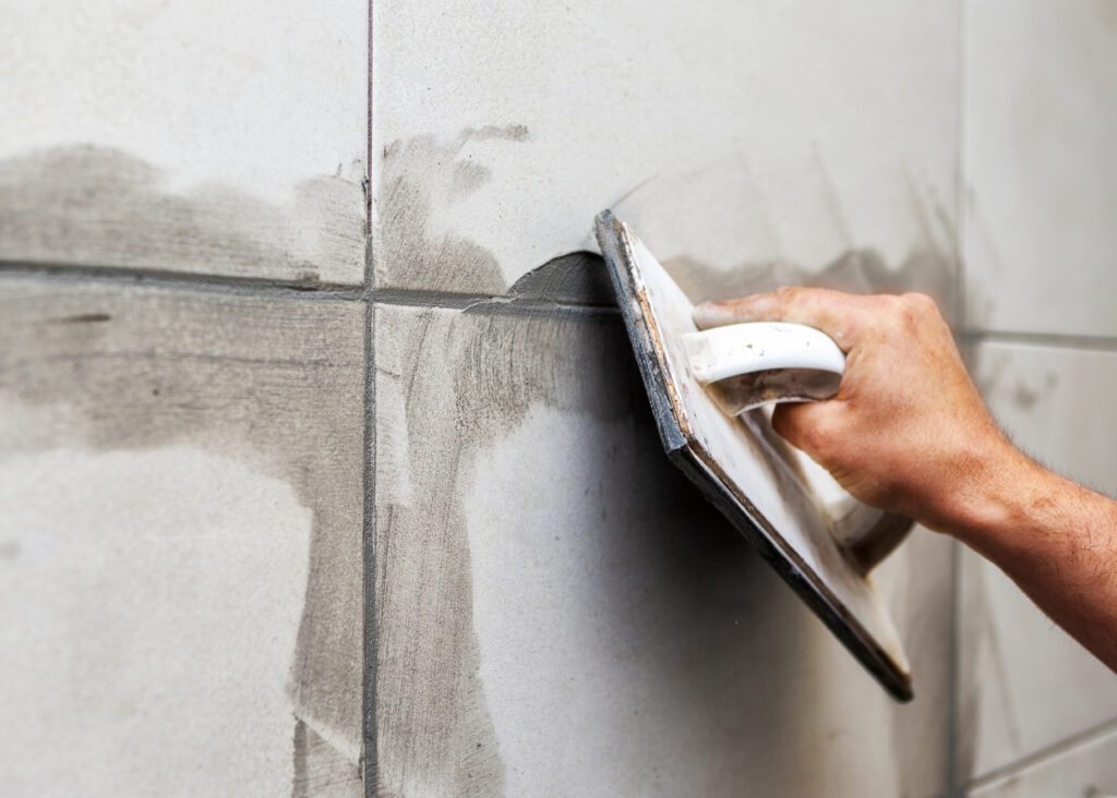 Grouting ceramic tiles. Tilers filling the space between tiles using a rubber trowel