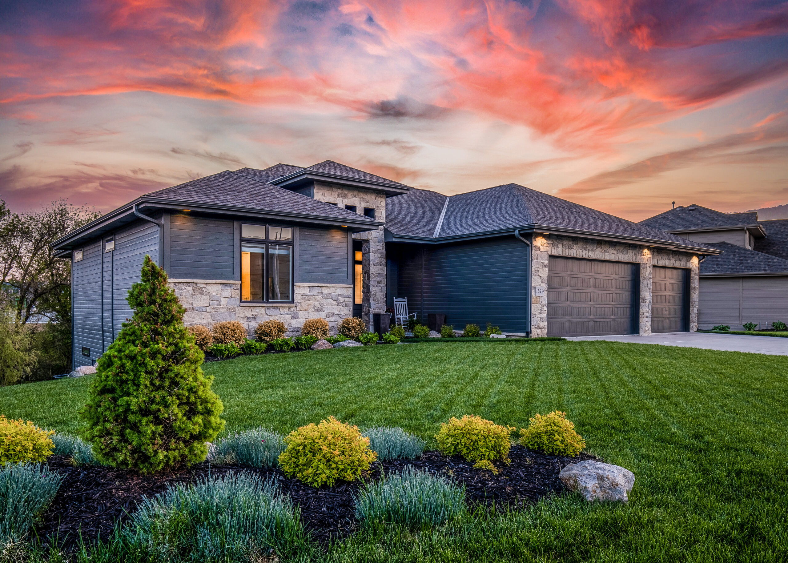 Luxury home during twilight golden hour with pink and purple sky and lush landscaping in Nebraska USA