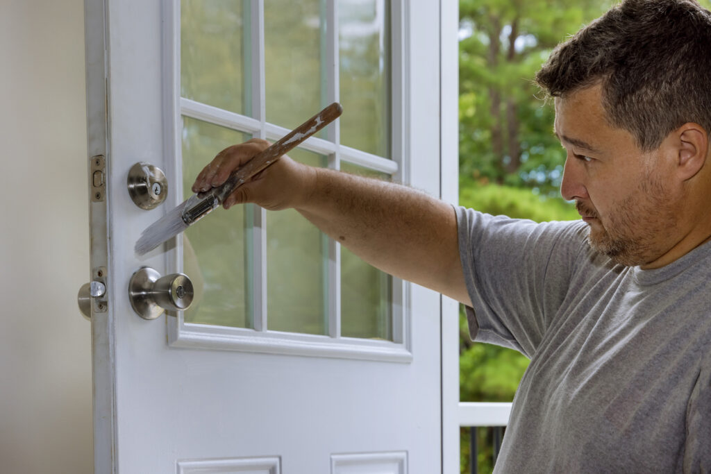 Painting wooden front doors with a using paintbrush was carried out by a worker