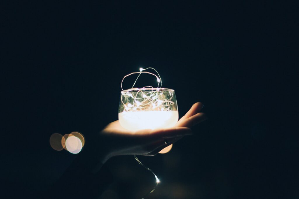 person holding clear glass candle light holder