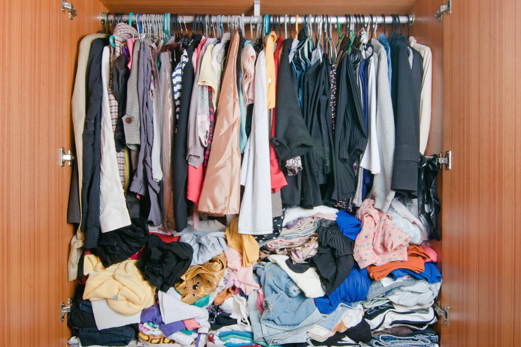 Pile of messy clothes in closet. Untidy cluttered woman wardrobe.