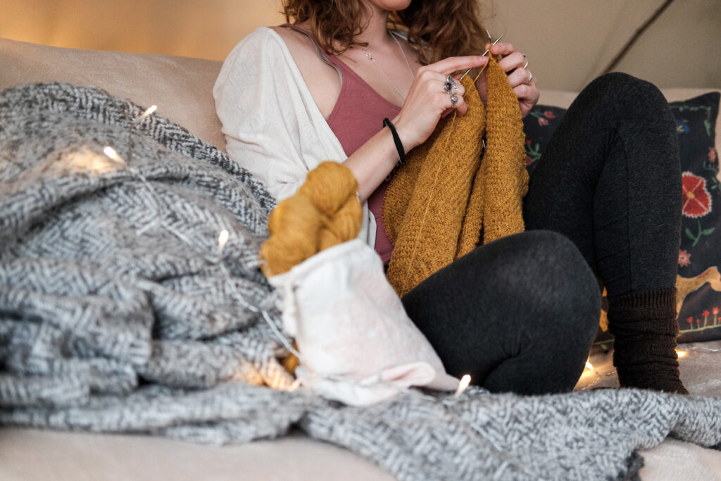 Woman sitting on a sofa while knitting a sweater