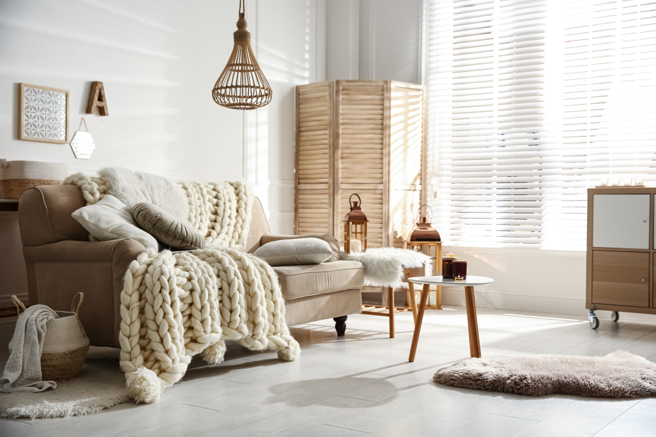 Cozy living room interior with beige sofa, knitted blanket and cushions