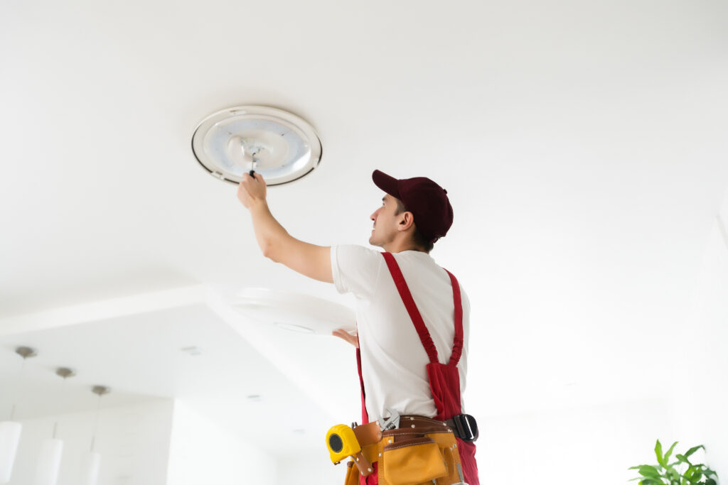 Electrician installs a chandelier on the ceiling. Construction concept