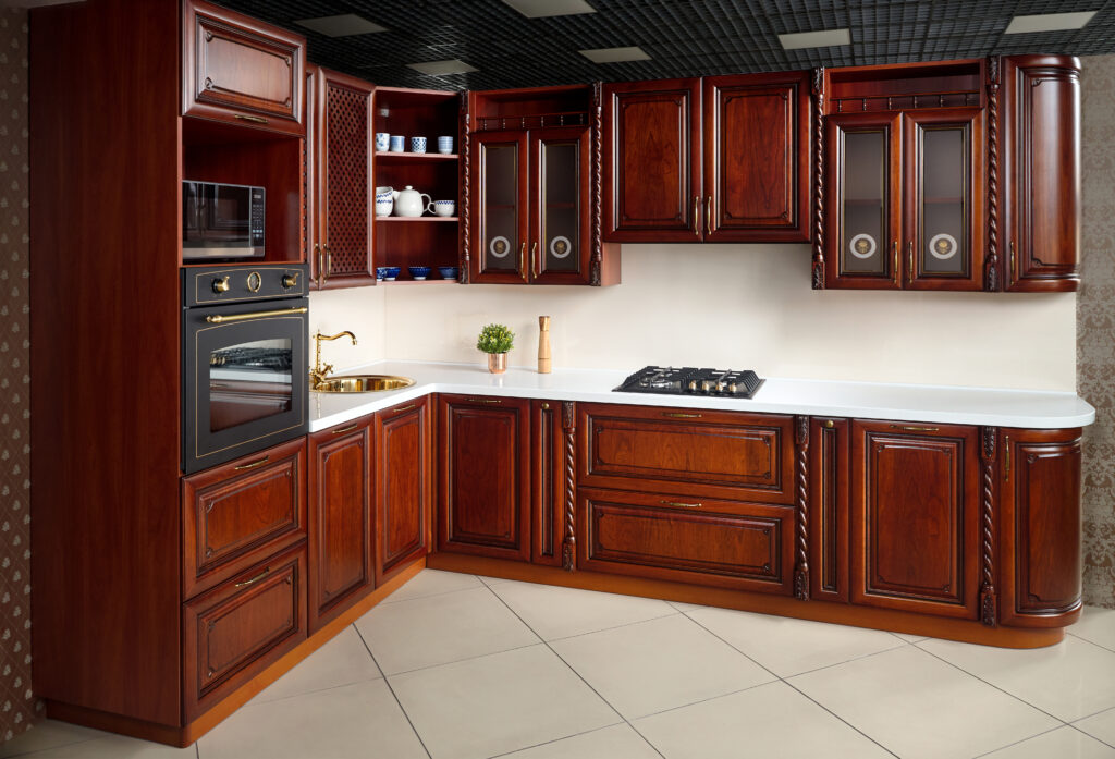 Interior of modern kitchen in classic style with golden elements cherry alder wood cabinetry with built-in appliances electric or induction hob electric oven stone sink and extractor fan.
