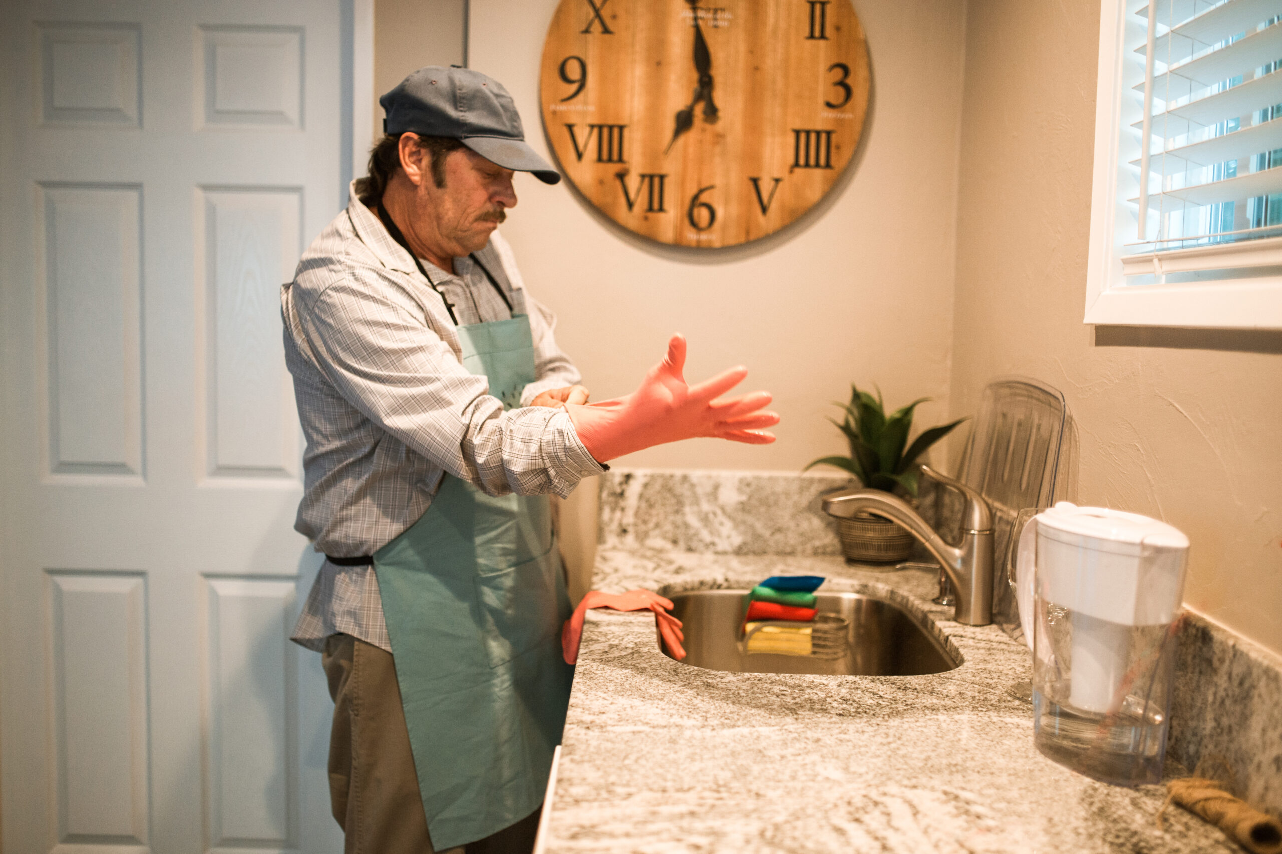 Senior man wearing a gloves standing in front of a sink