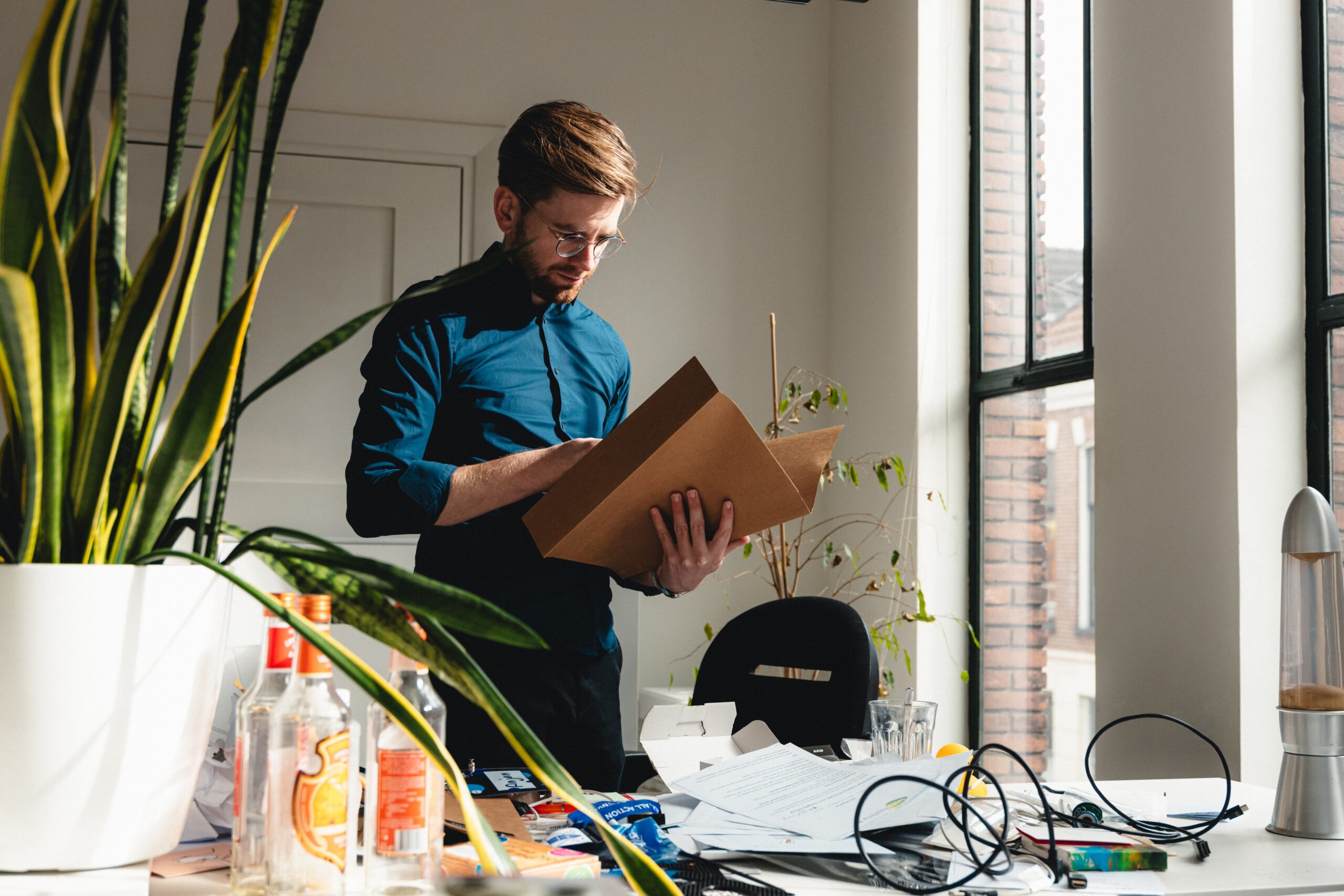 A man cleaning out a desk and looking through the final bookkeeping of a closing business. The smell of bankruptcy lingering in the air.