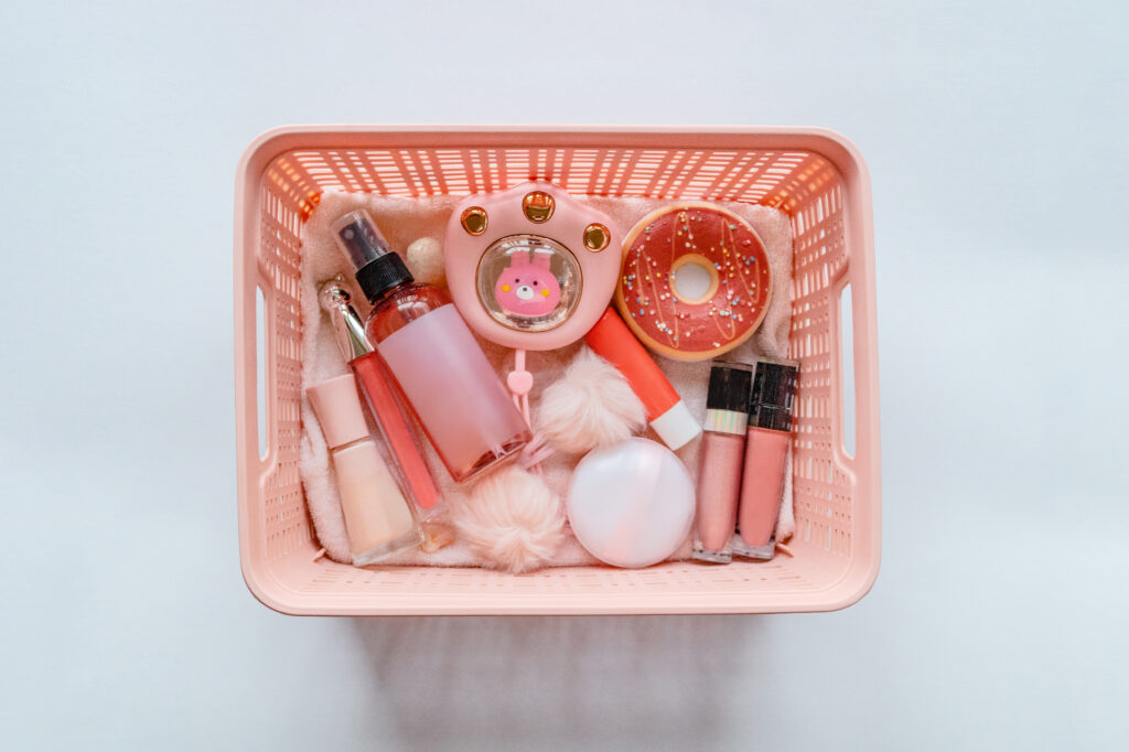 Collection of cosmetic products in a pink storage bin