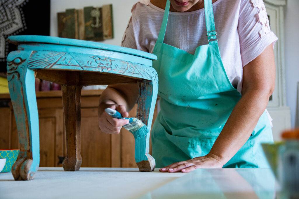 Close-up of craftwoman's hands holding brush and painting antique furniture