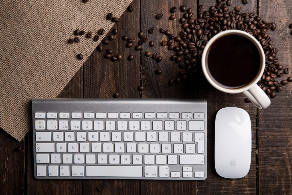 Flat lay photography of apple magic keyboard mouse and mug filled with coffee beside beans