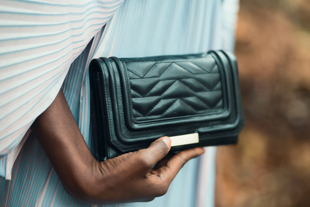 Person holding quilted black leather clutch bag