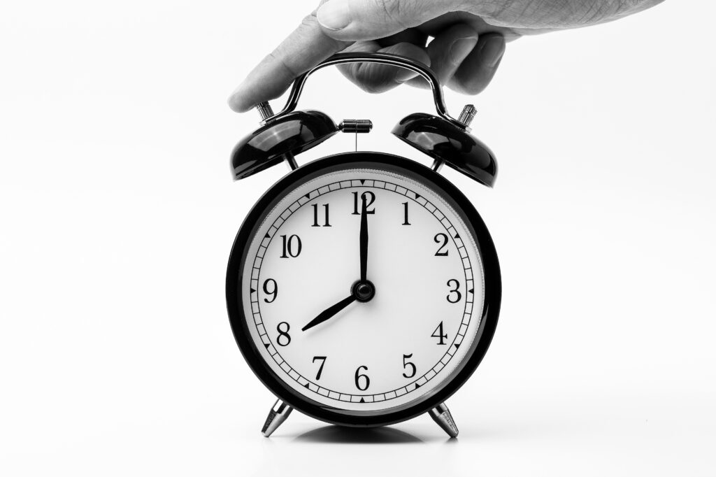 Person touching black two bell alarm clock