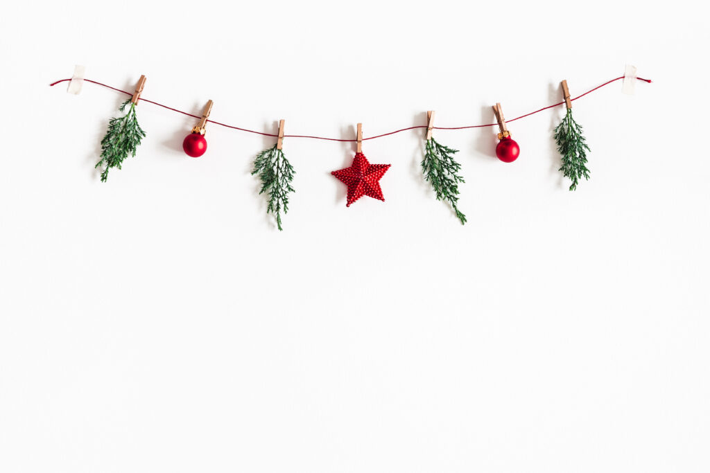 Christmas composition. Garland made of red balls and fir tree branches on white background. Christmas, winter, new year concept. Flat lay, top view, copy space