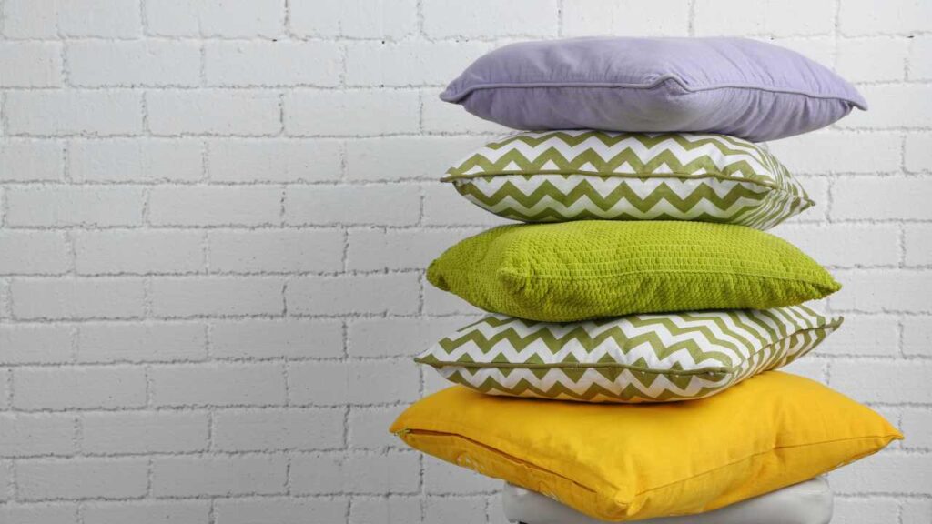 a stack of pillows in front of a white brick wall