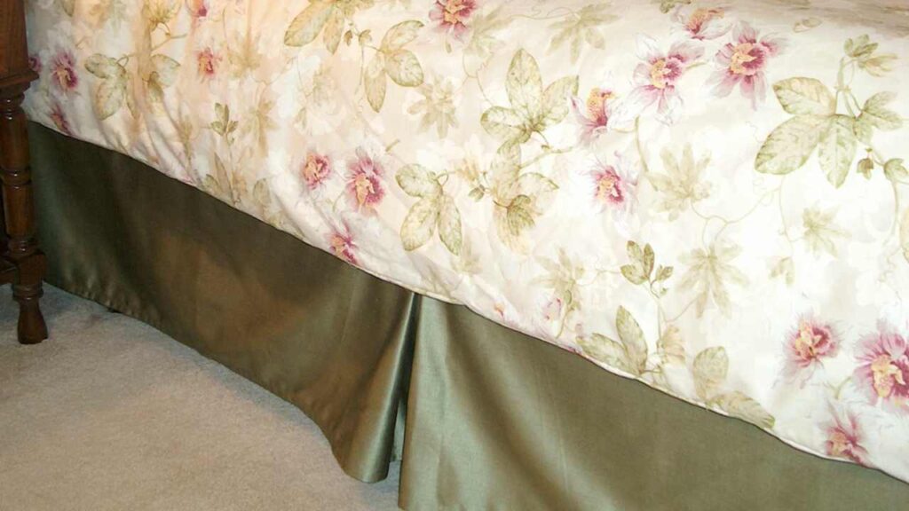 a bed with a floral comforter and a dresser next to it