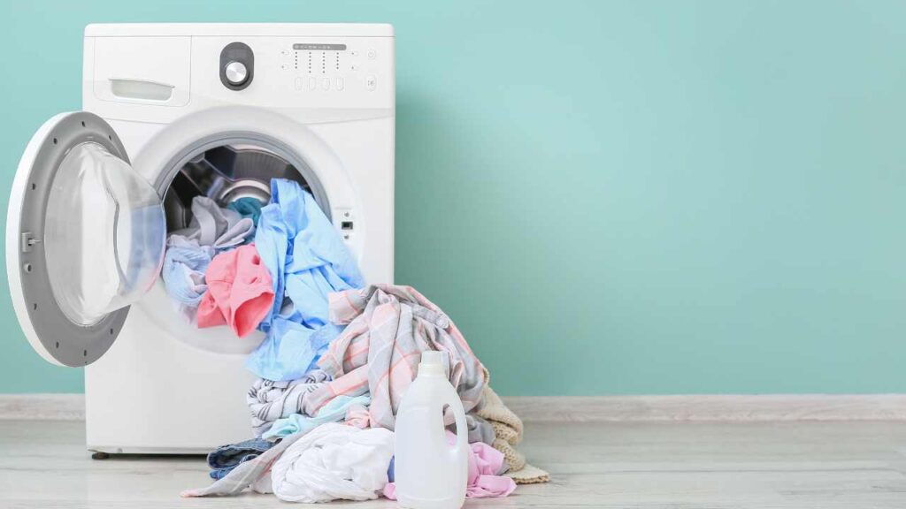 a washer and dryer full of clothes in front of a turquoise wall