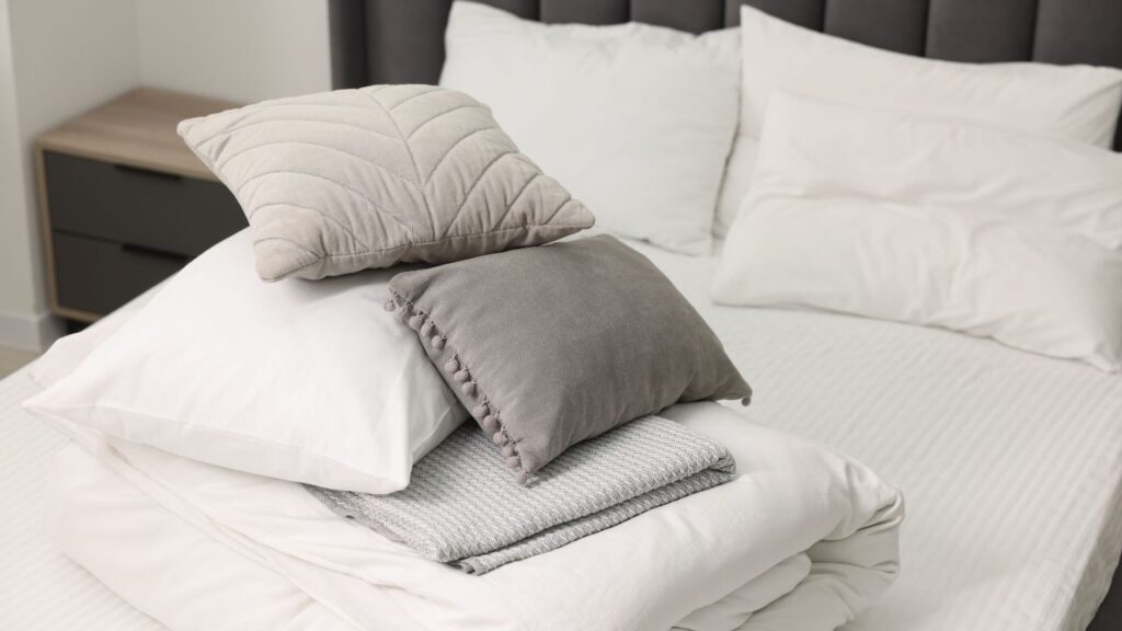 a pile of white pillows on top of a bed