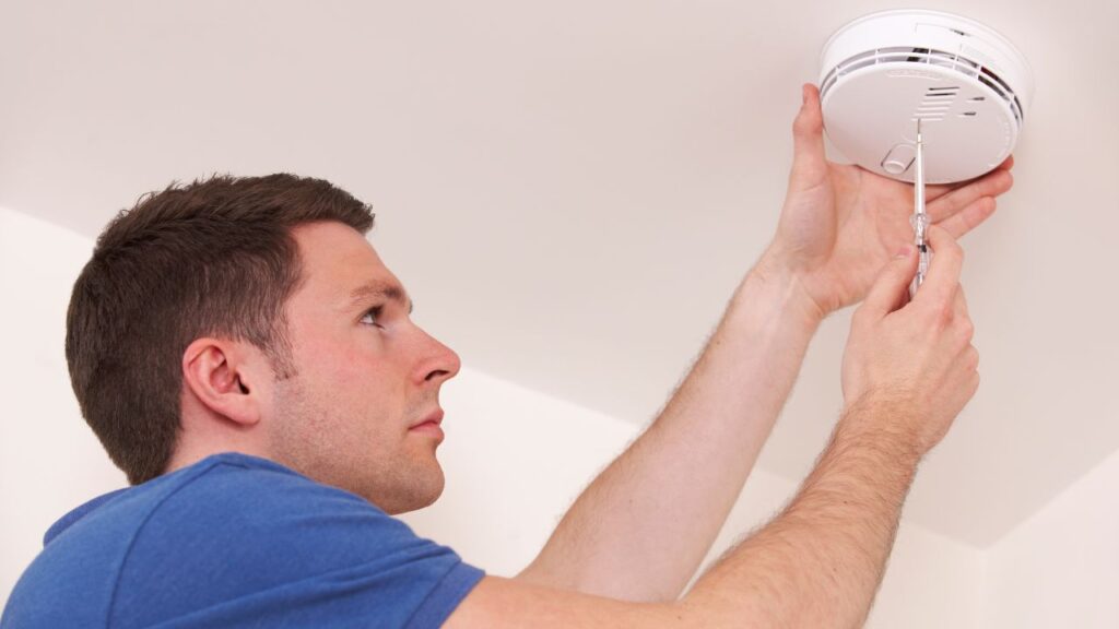 a person installing a smoke detector in a room