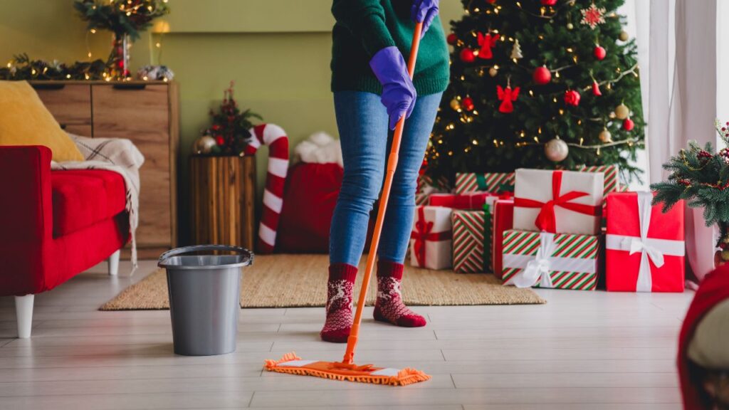 a person is cleaning the floor with a mop in front of a Christmas tree