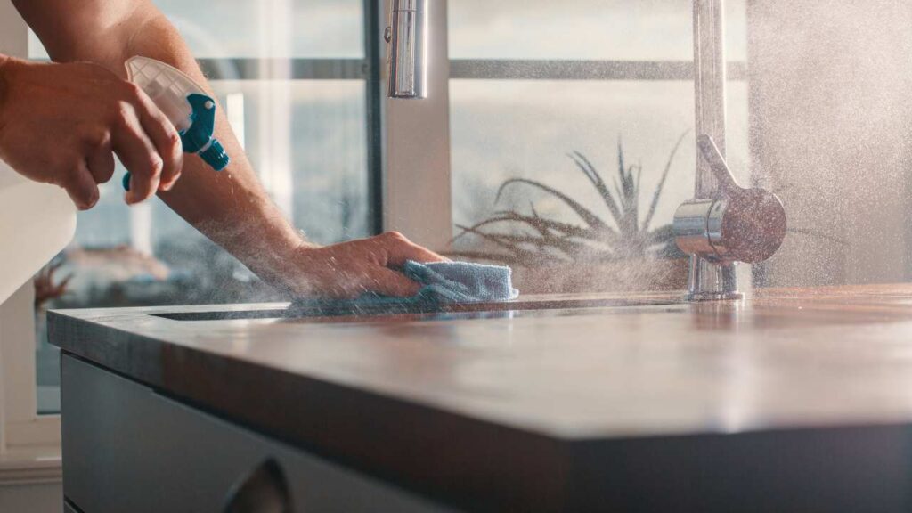 a person cleaning a countertop with a sponge