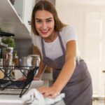 a person in an apron is washing dishes in the kitchen