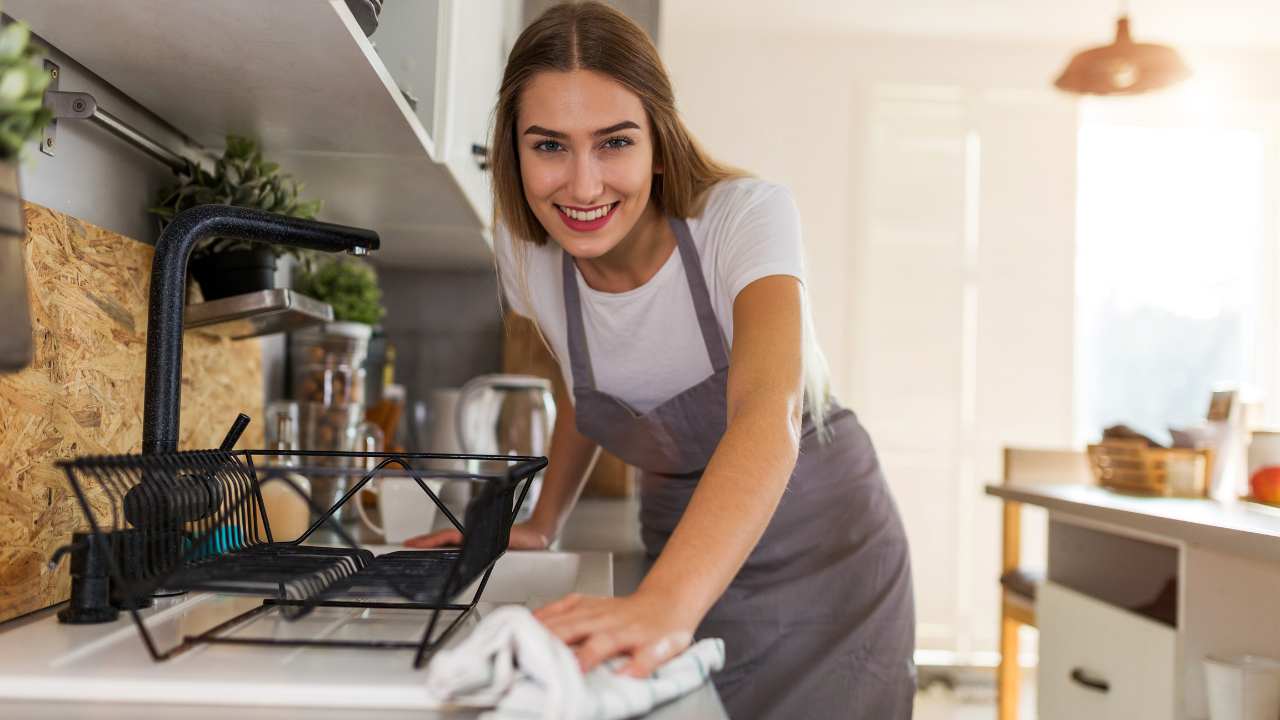 a person in an apron is washing dishes in the kitchen