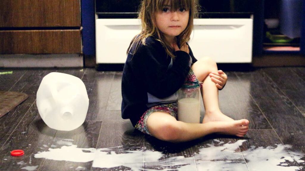 a person sitting on the floor next to a jug of milk