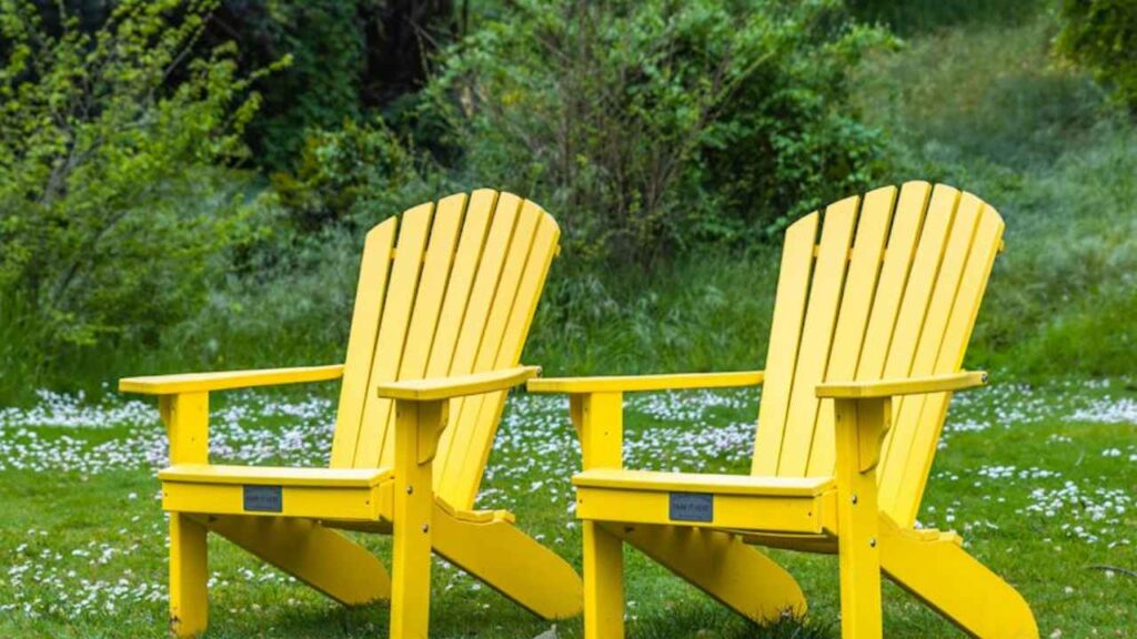 a pair of yellow Adirondack chairs sitting in the grass